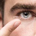 Mężczyzna trzymający soczewkę kontaktową – soczewki nocne jako nowoczesna metoda korekcji wzroku