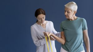 Terapeuta ręki pomaga starszej kobiecie wykonywać ćwiczenia na rękę